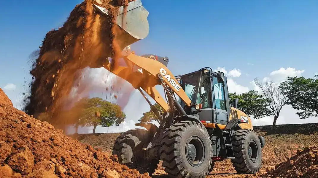 Pá-carregadeira CASE 621E movimentando terra em operação.
